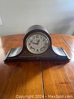 Front view of the Plymouth mantle clock showing wooden case with curved top and decorative base.