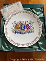 Top view of the Queen Elizabeth Silver Jubilee commemorative plate in original green satin-lined box, showing front decorative design and identification text around edge.
