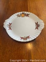 Full view of Royal Albert cake plate on wooden table showing tartan ribbon and crest design.