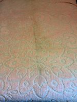 Close-up of the double size pink chenille bedspread showing the textured floral and geometric pattern with plain edges.