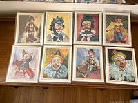 Photo showing full set of eight clown prints laid out on a table, each print about 10 x 8.5 inches, all brand new.