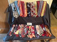 Full view of 23 men's vintage neckties draped over a chair showing various patterns and colors typical of the 1940s-1950s era.