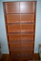 Front-facing image of medium brown wooden cabinet with six shelves designed for CD storage, showing size and shelf arrangement.