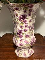 Porcelain vase with purple violet flowers on white background, flared top, scalloped base, approx. 10 inches tall.