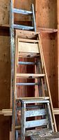 Five ladders stacked, showing aluminum extension ladder and four wood ladders leaning against wall
