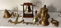 Wide view showing all brass nautical items including multiple bells, decorative anchor, and door knocker