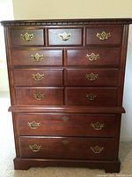Front view of the tall dresser showing six drawers with brass pulls and dark cherry veneer.