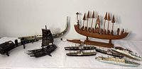Photo showing the entire set of maritime collectibles including carved wooden boats and several small ship models arranged on a white surface.