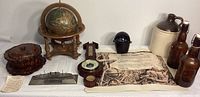 Overall view of lot showing wood globe, chrysanthemum wood box, barometer, pewter ship, ceramic jug, beer bottles, and documents