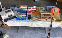 Overview of fishing rods, reels, tackle boxes, fish finder and radio on table