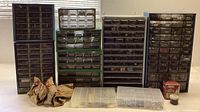Wide view of multiple hardware storage cabinets and paper bags filled with nails and screws, plus clear plastic organizers containing assorted hardware.