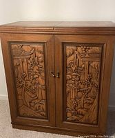 Closed front view showing carved relief panels on cabinet doors