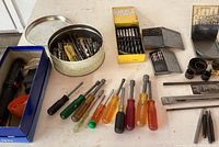 Wide shot of screwdrivers and drill bits laid out on table.
