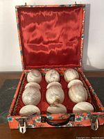 Top view showing six onyx wine glasses arranged inside a flower-patterned box with red satin lining.