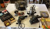 Full view of all tools on table including grinder, sander, drill, stapler kit and saw blade