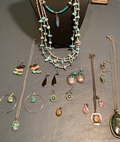 Overview of entire lot showing necklaces, earrings, and pendants on a dark flat surface.