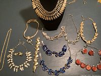 Overview of all metal necklaces and bracelets including a wide collar necklace, blue and red enamel pieces, and leaf motif designs