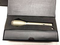 Microphone in open black case with foam padding, showing the full microphone body.