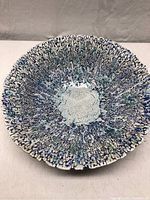 Angled top view of plate showing crackle glaze pattern and blue-green splatter
