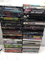 Photo showing a large stack of DVDs including titles like 10 Cloverfield Lane, The Big Bang Theory, Iron Man, Doctor Strange, Game of Thrones season 2, The Strain season 1, Ray Donovan season 5, and others.