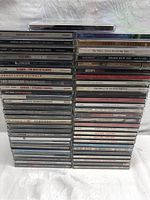 Photo showing stacked rock and soft rock music CDs with titles visible including David Bowie, Eric Clapton, Smokey Robinson, Blondie, Heart, Led Zeppelin, Gowan, Daft Punk, Rush, Alice Cooper, Rockhead, Sting, Bryan Adams, and others.