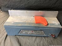 Front and top-down view of the jointer-planer unit showing the blue base, silver metal working surface and red push block.