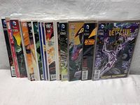Stack of 11 comic books fanned out showing spines and front covers including Batman, Detective Comics, and other DC titles