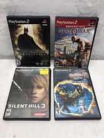 All four PS2 game cases laid out on gray fabric background