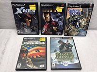 Five PlayStation 2 game cases arranged in 2 rows on a white background, titles are X-Men Legends, Iron Man, Silent Scope, Conflict Desert Storm, Medal of Honor Frontline.