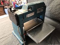 Angled view showing machine body, motor housing, infeed/outfeed tables