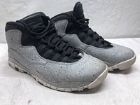 Side profile showing the cement gray speckled upper, black tongue and laces, and white outsole with black accents.