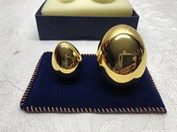 Two gold eggs on navy velvet mat with foam-lined box in background