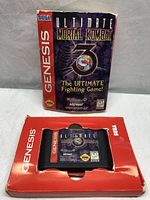 Front view of the Ultimate Mortal Kombat 3 box and Sega Genesis cartridge in red cardboard insert.