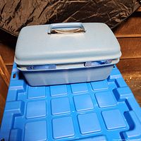 Front angled view of the blue Samsonite cosmetic train case showing the handle and top.