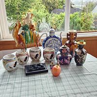 Wide shot of all Asian decor items on table showing overall assortment and scale with apple for size reference
