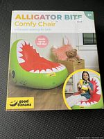 Front of packaging box showing the inflatable alligator mouth chair in green with red, white teeth design. Displays brand Good Banana and notes it holds up to 150 lbs.