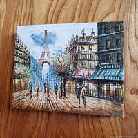 Front view of hand-painted canvas showing a Paris scene with Eiffel Tower, people walking, and city buildings.
