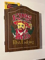 Closed wooden cabinet with Kings Head Pub & Lodging artwork on front.