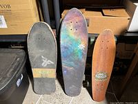 Top view of three skateboards showing the grip tape and deck graphics: Land Yachtz on left, Globe in middle, Arbor on right