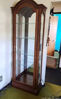 Full front and side view of the tall wooden display cabinet with glass and mirror panels.