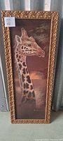 Full view of framed giraffe art print showing elongated vertical composition and detailed giraffe profile with ornate gold frame.