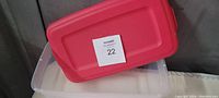 Photo showing the Sterilite clear plastic storage container with its red lid placed at an angle on top.