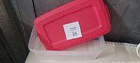 Clear plastic storage container with a red lid on top showing size and condition.