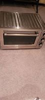 Front and top view of the stainless steel Cuisinart toaster oven showing controls and handle