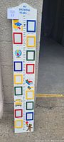 Front view of 40-inch tall wooden picture frame with colorful photo frames for each grade year, visible labels and decorative school-themed illustrations.