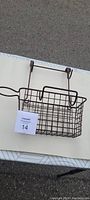 Brown metal wire basket designed to hang over a door, with grid structure basket and hooks on top.