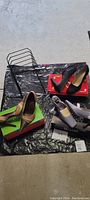 Photo of two metal step file/letter/mail holders and three pairs of women's high heel shoes on top of black plastic sheet with shoe boxes and dust bags visible.