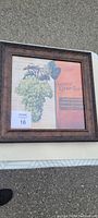 Photo of framed wall artwork showing bunch of green grapes and text against a warm background