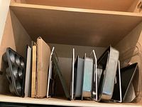 Shelf of metal baking pans with wire dividers showing various shapes and sizes including muffin tin and rectangular pans