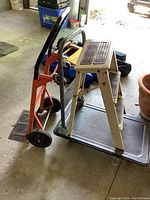 Two dollies and one step stool arranged together on a garage floor.